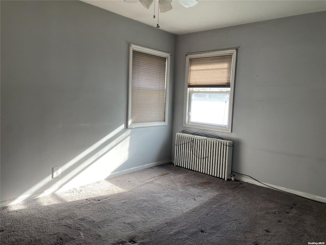 carpeted empty room with ceiling fan and radiator