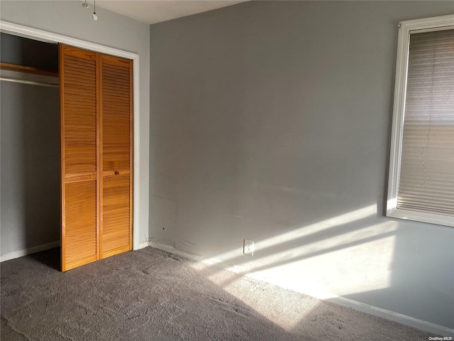 unfurnished bedroom with dark colored carpet and a closet