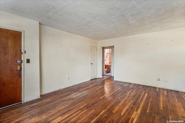 empty room with a textured ceiling and dark hardwood / wood-style floors