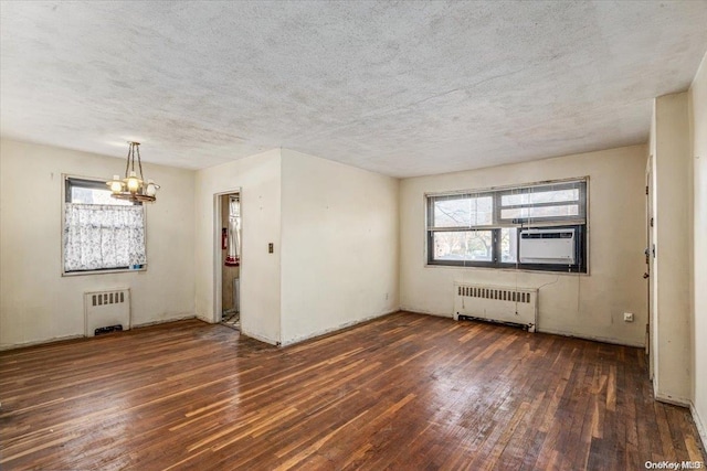 unfurnished room with radiator heating unit, a textured ceiling, dark hardwood / wood-style floors, and cooling unit