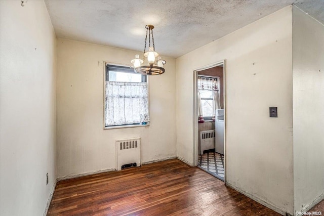 unfurnished dining area with radiator, plenty of natural light, and dark hardwood / wood-style flooring