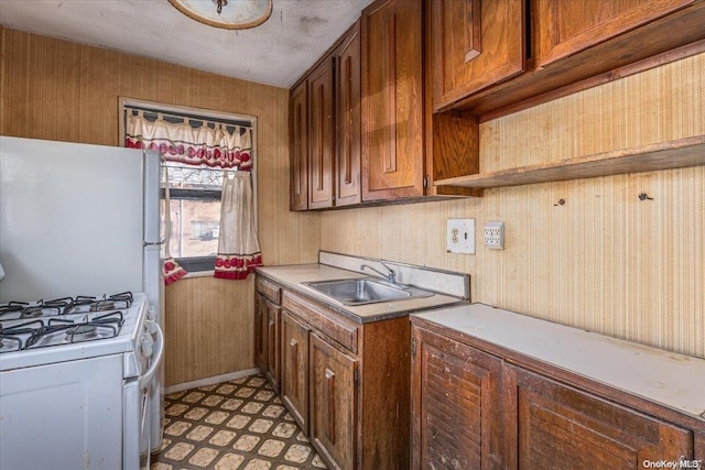 kitchen featuring white appliances, sink, and wooden walls