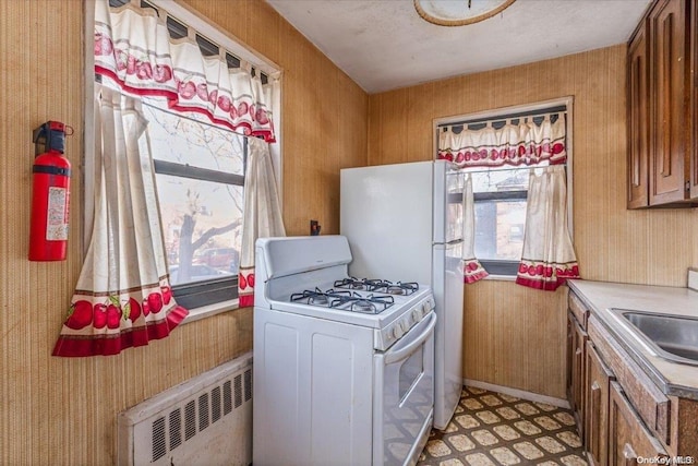 kitchen with radiator, white gas stove, and sink