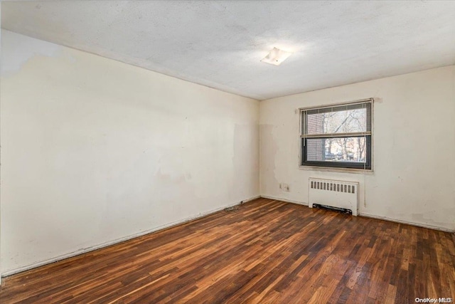 empty room featuring a textured ceiling, radiator, and dark hardwood / wood-style floors