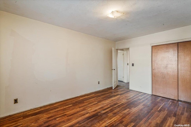 unfurnished bedroom featuring a closet, dark hardwood / wood-style flooring, and a textured ceiling