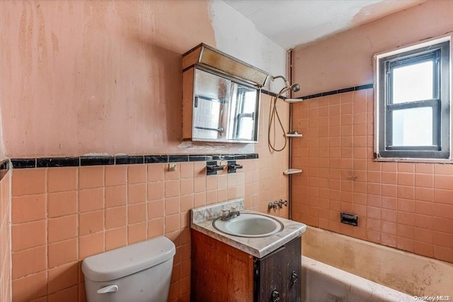 full bathroom with vanity, toilet, tiled shower / bath, and tile walls