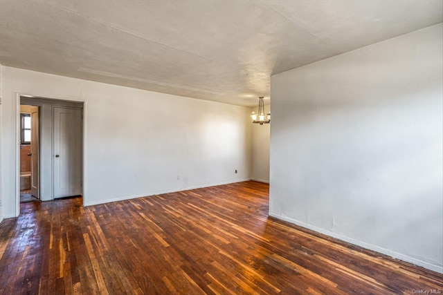 spare room featuring a chandelier and dark hardwood / wood-style flooring