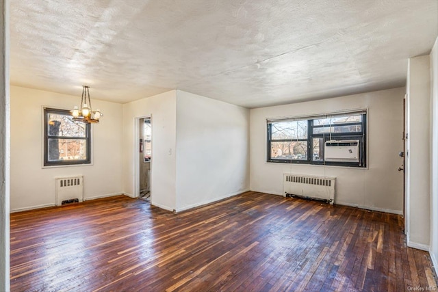 spare room featuring dark hardwood / wood-style flooring, cooling unit, radiator heating unit, and an inviting chandelier