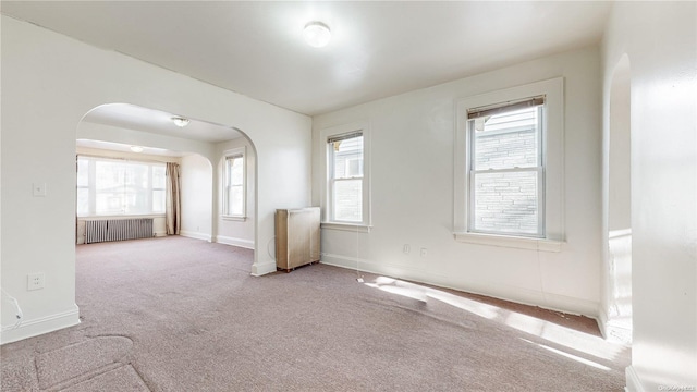 spare room with light carpet and radiator