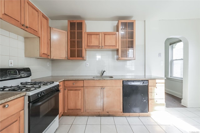 kitchen featuring dishwasher, sink, gas range, decorative backsplash, and light stone countertops