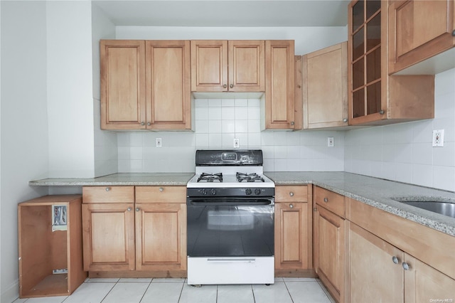 kitchen with gas stove, light stone counters, light tile patterned flooring, and tasteful backsplash