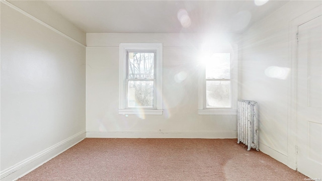 empty room featuring light carpet and radiator heating unit