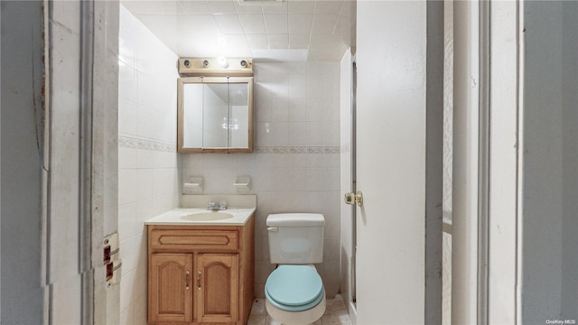 bathroom with vanity, toilet, and tile walls