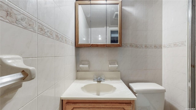 bathroom with backsplash, vanity, tile walls, and toilet