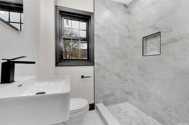 bathroom with sink, toilet, and tiled shower