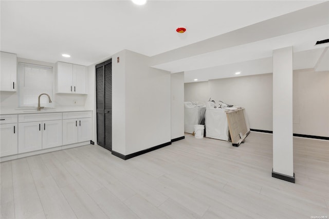 interior space featuring light wood-type flooring, separate washer and dryer, and sink