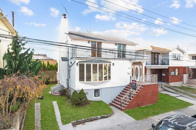 view of front of house with a front yard and a balcony