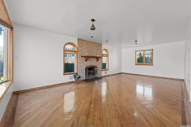 unfurnished living room featuring a wealth of natural light, a large fireplace, and wood-type flooring