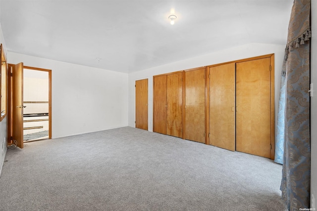 unfurnished bedroom featuring light colored carpet and lofted ceiling