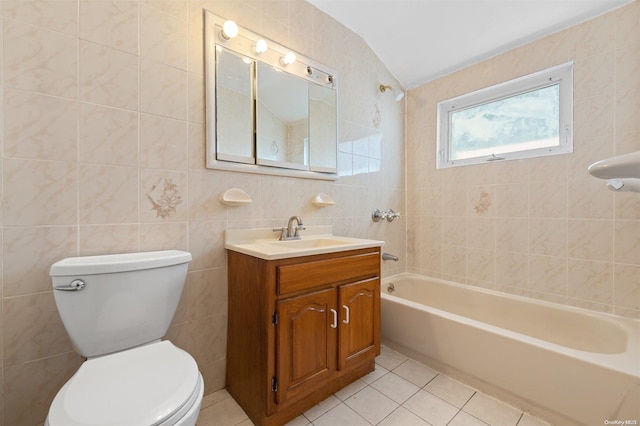 full bathroom with vanity, tile patterned floors, tiled shower / bath combo, toilet, and tile walls