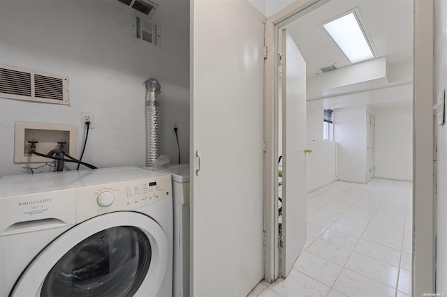 clothes washing area with light tile patterned floors and washer and dryer