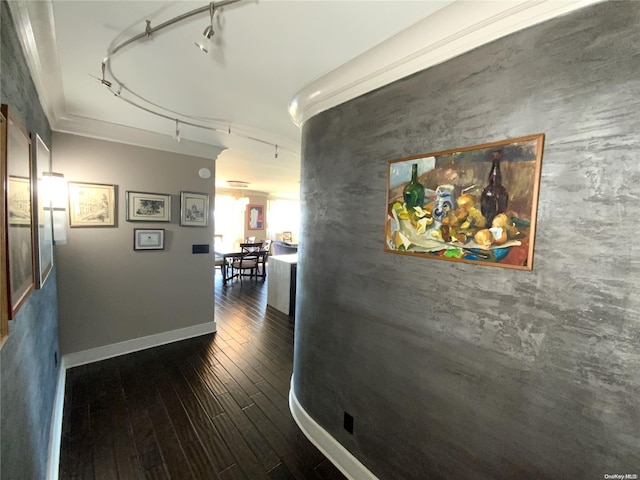 hallway with dark hardwood / wood-style flooring, track lighting, and ornamental molding