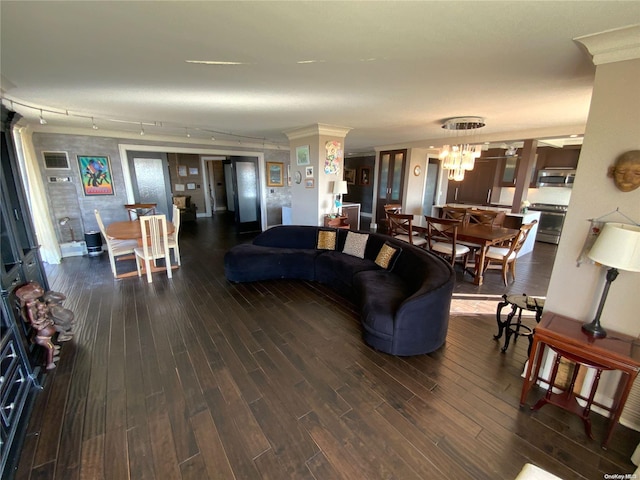 living room with a chandelier, rail lighting, dark hardwood / wood-style floors, and crown molding