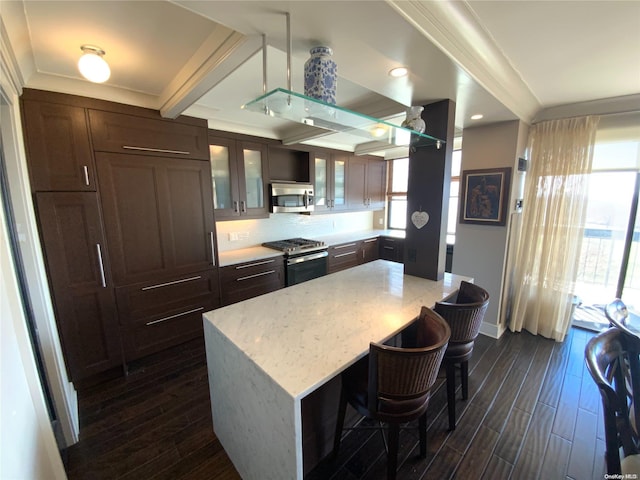 kitchen featuring stainless steel appliances, light stone counters, dark hardwood / wood-style floors, a breakfast bar, and a kitchen island