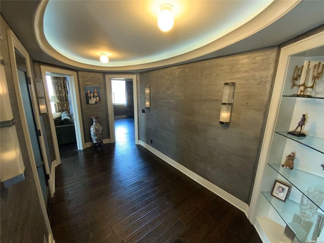 corridor featuring dark wood-type flooring and a tray ceiling