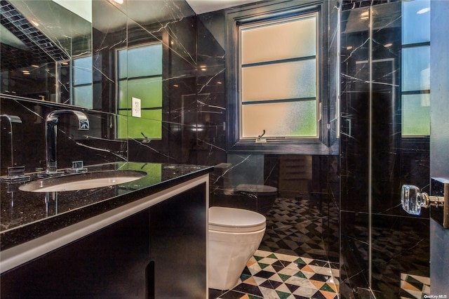 bathroom featuring tile patterned floors, toilet, vanity, a shower with shower door, and tile walls