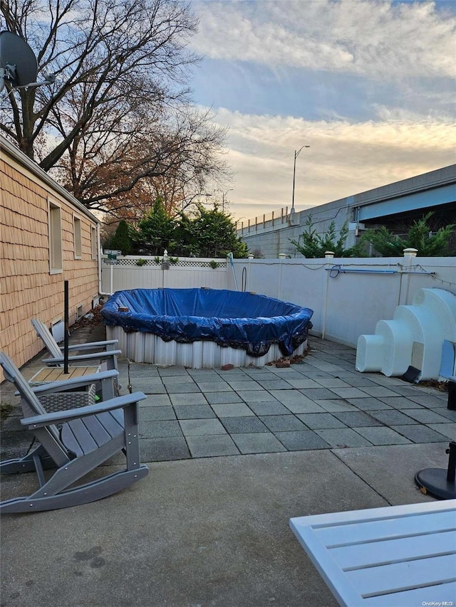 pool at dusk featuring a patio