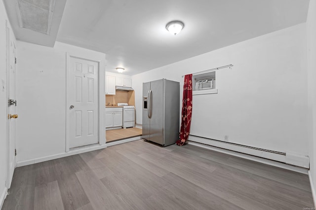 spare room with light wood-type flooring, a wall unit AC, and a baseboard radiator