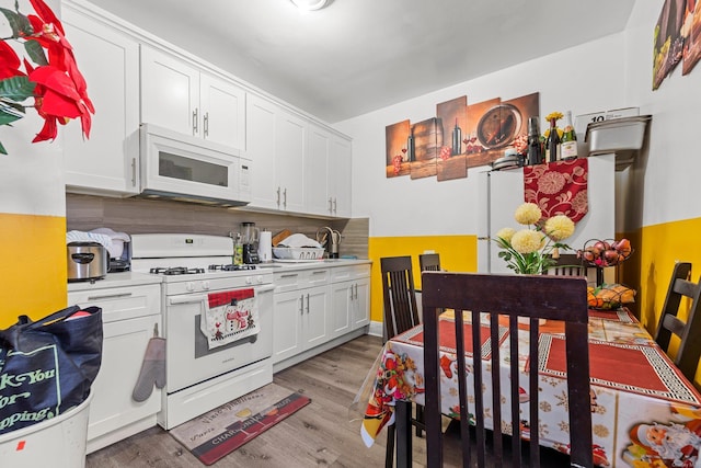 kitchen featuring light wood-type flooring, white cabinetry, and white appliances