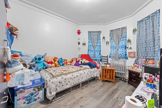 bedroom with crown molding and light hardwood / wood-style floors