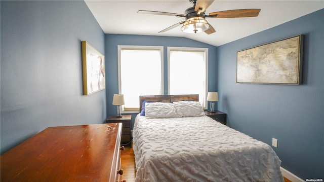 bedroom with multiple windows, ceiling fan, wood-type flooring, and lofted ceiling