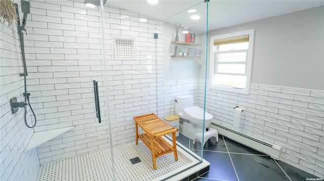 bathroom featuring a baseboard heating unit, tile patterned floors, toilet, a shower with shower door, and tile walls