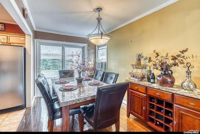 dining space featuring light hardwood / wood-style flooring and crown molding