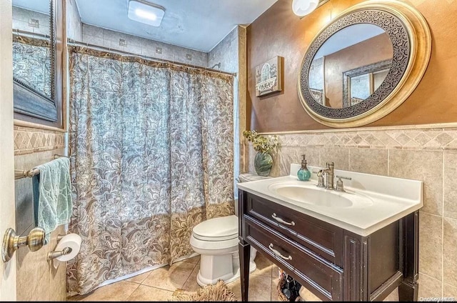 bathroom with tile patterned flooring, vanity, toilet, and tile walls