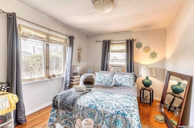 bedroom featuring wood-type flooring, cooling unit, multiple windows, and ornamental molding