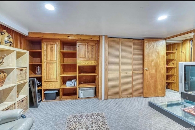 living room with carpet flooring, wood walls, and an AC wall unit