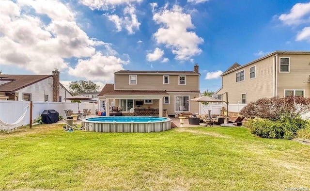 rear view of house featuring a lawn and a fenced in pool