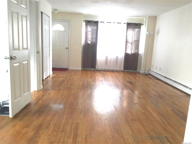 unfurnished room with dark hardwood / wood-style flooring and a baseboard heating unit