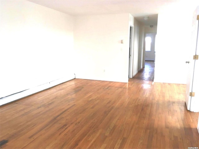 spare room with baseboard heating and dark wood-type flooring