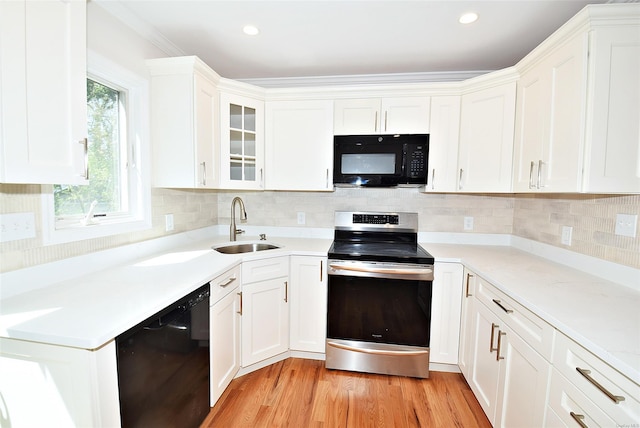 kitchen with black appliances, a sink, white cabinetry, light countertops, and light wood-type flooring