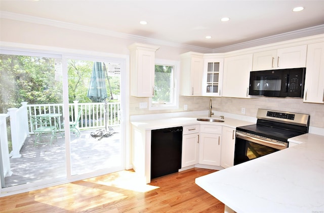 kitchen featuring black appliances, a sink, white cabinetry, crown molding, and decorative backsplash