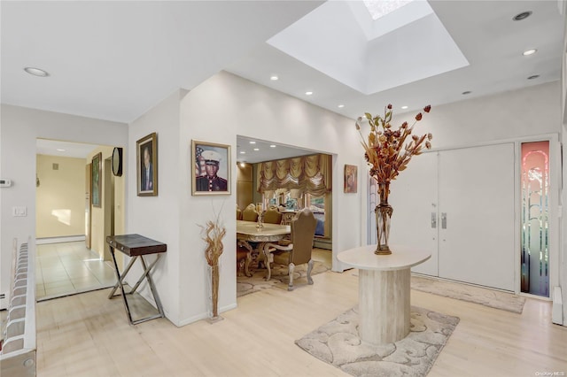 entryway with light hardwood / wood-style floors, a skylight, and a baseboard heating unit