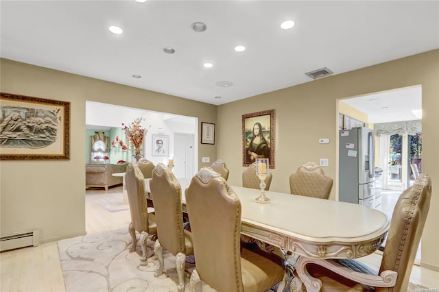 dining space with light wood-type flooring and baseboard heating