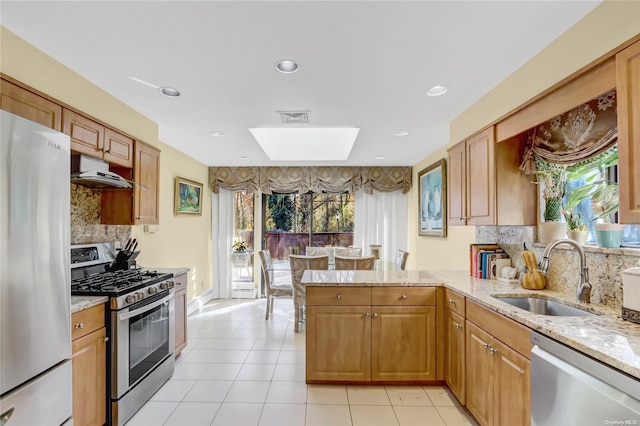 kitchen with sink, decorative backsplash, light stone counters, kitchen peninsula, and stainless steel appliances