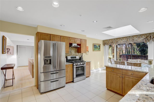 kitchen featuring backsplash, light stone counters, light tile patterned flooring, and stainless steel appliances