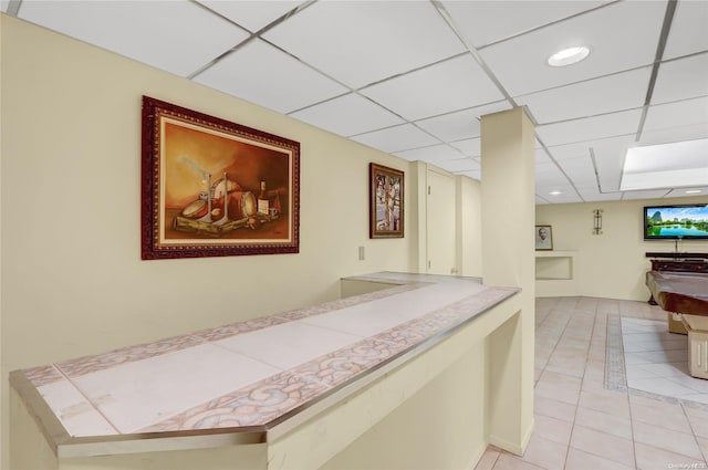 hallway with light tile patterned floors and a drop ceiling